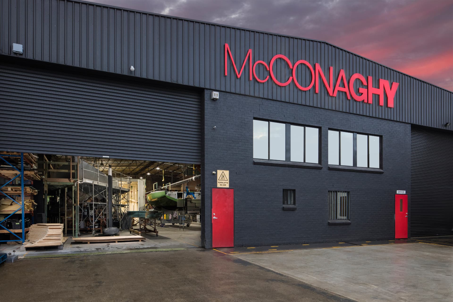 McConaghy Australia manufacturing facility exterior at dusk with illuminated red McConaghy signage