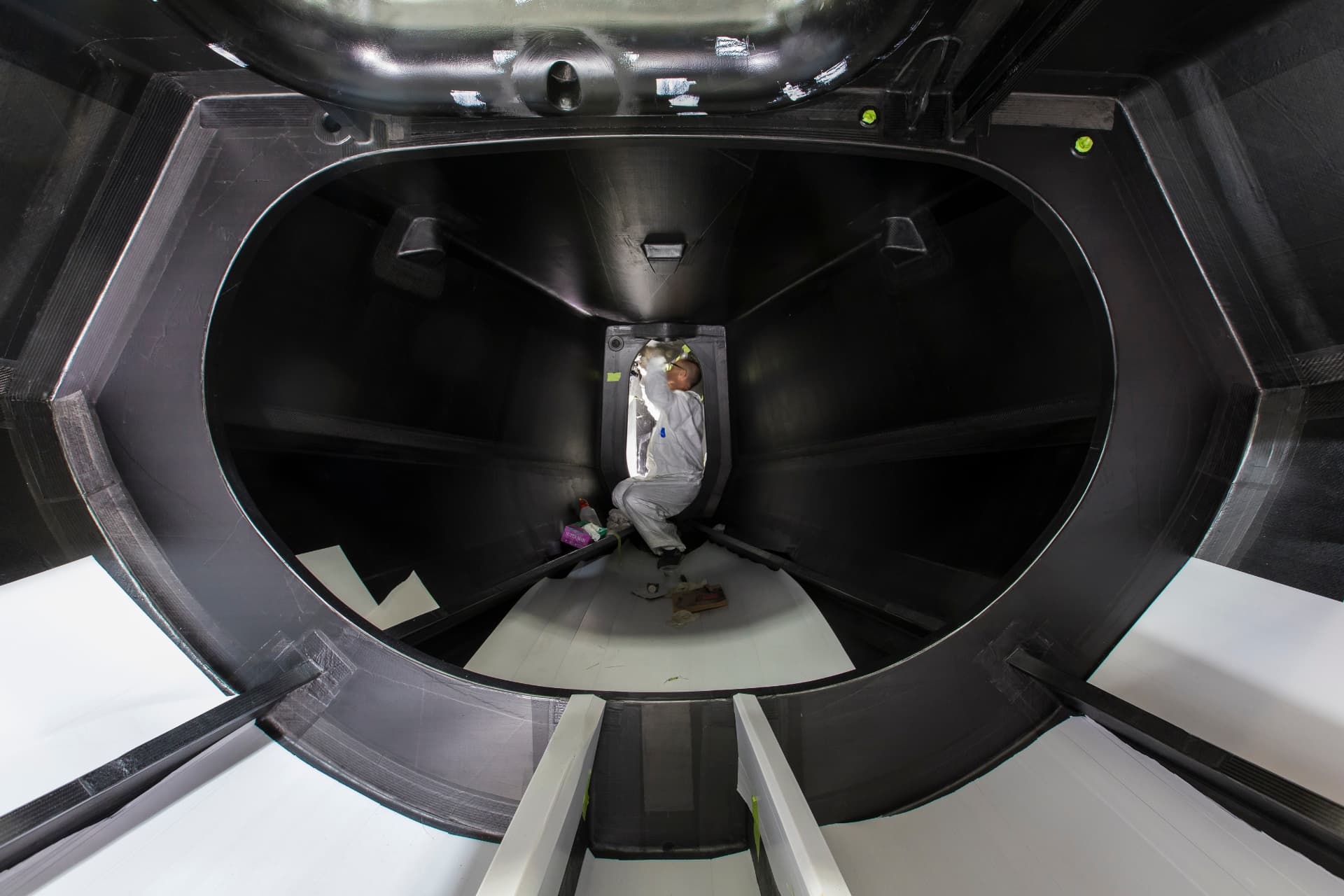 Technician working inside a large carbon composite hull structure