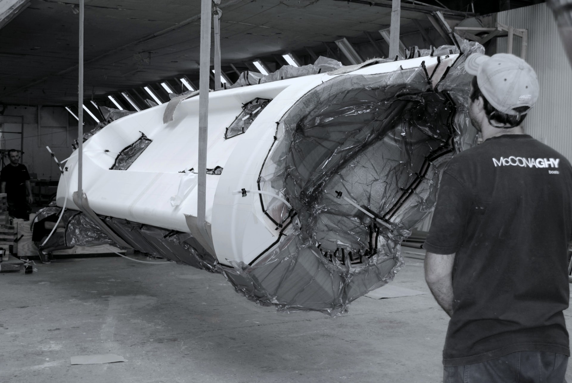 Composite hull section lifted under vacuum bagging while a McConaghy technician looks on