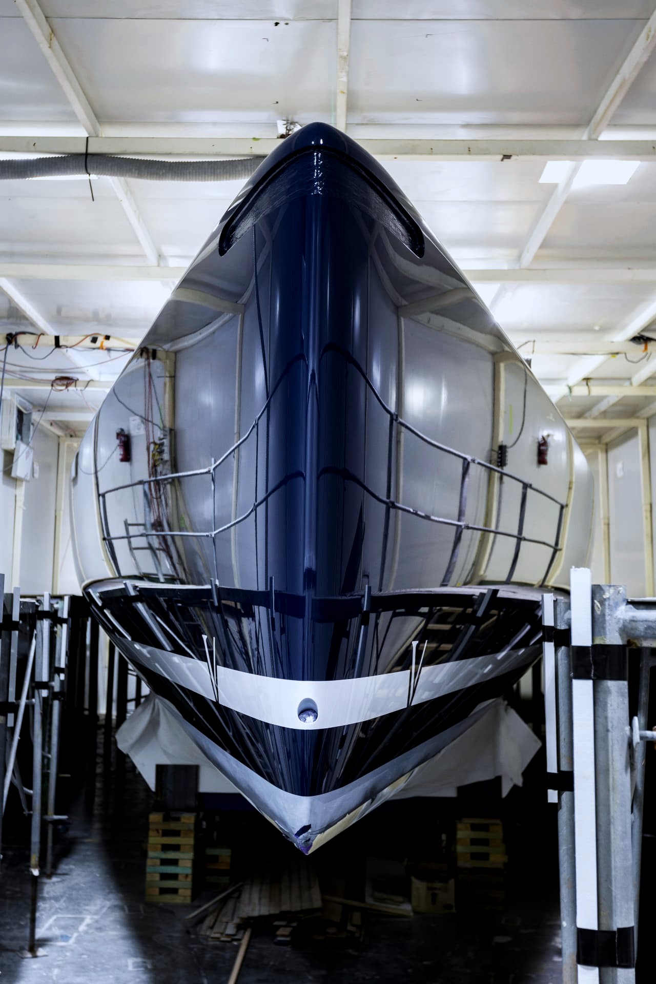 Deep navy racing yacht hull on cradles inside the McConaghy Australia refit shed