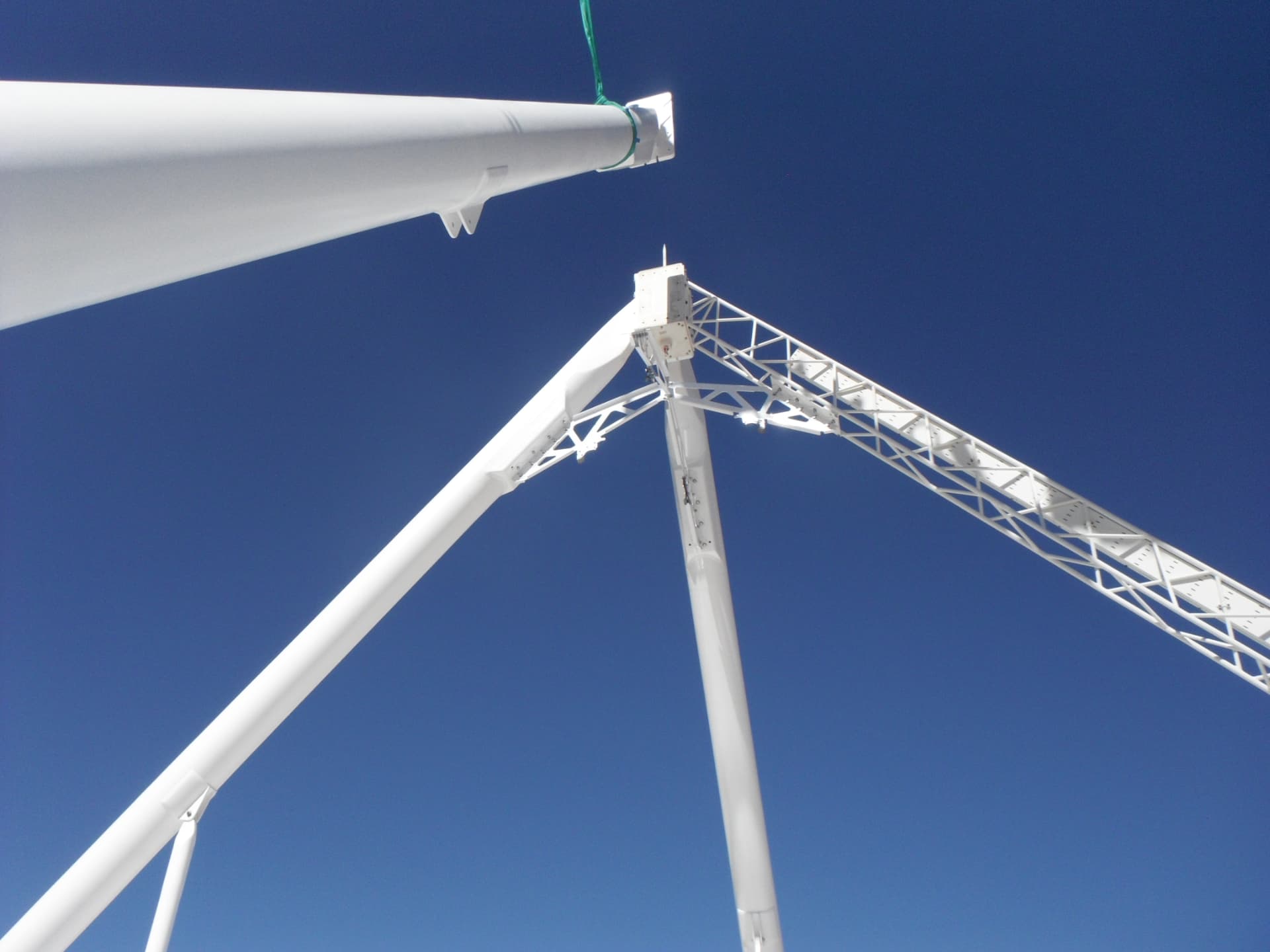 Composite antenna boom and feed structure being lifted against a deep blue sky